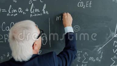 聪明的资深教授在课堂上用黑板书写方程式的后视图